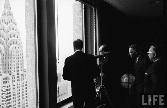 "Businessman Earl Huntington and others gazing at the Chrysler Building from upper floor office in the Pan Am building." 1962